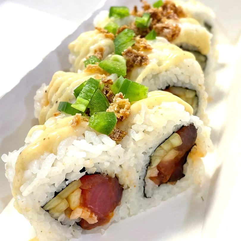 Sushi Box TB sushi rolls with white sauce, green peppers, and crispy toppings in a white container.